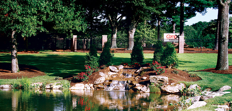 Entrance to the CompX National facility, showing the large entrance sign and beautiful pond out front